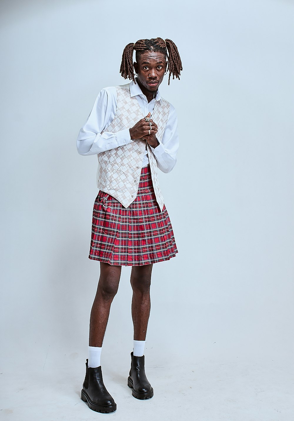 a man in a kilt and boots standing in front of a white background