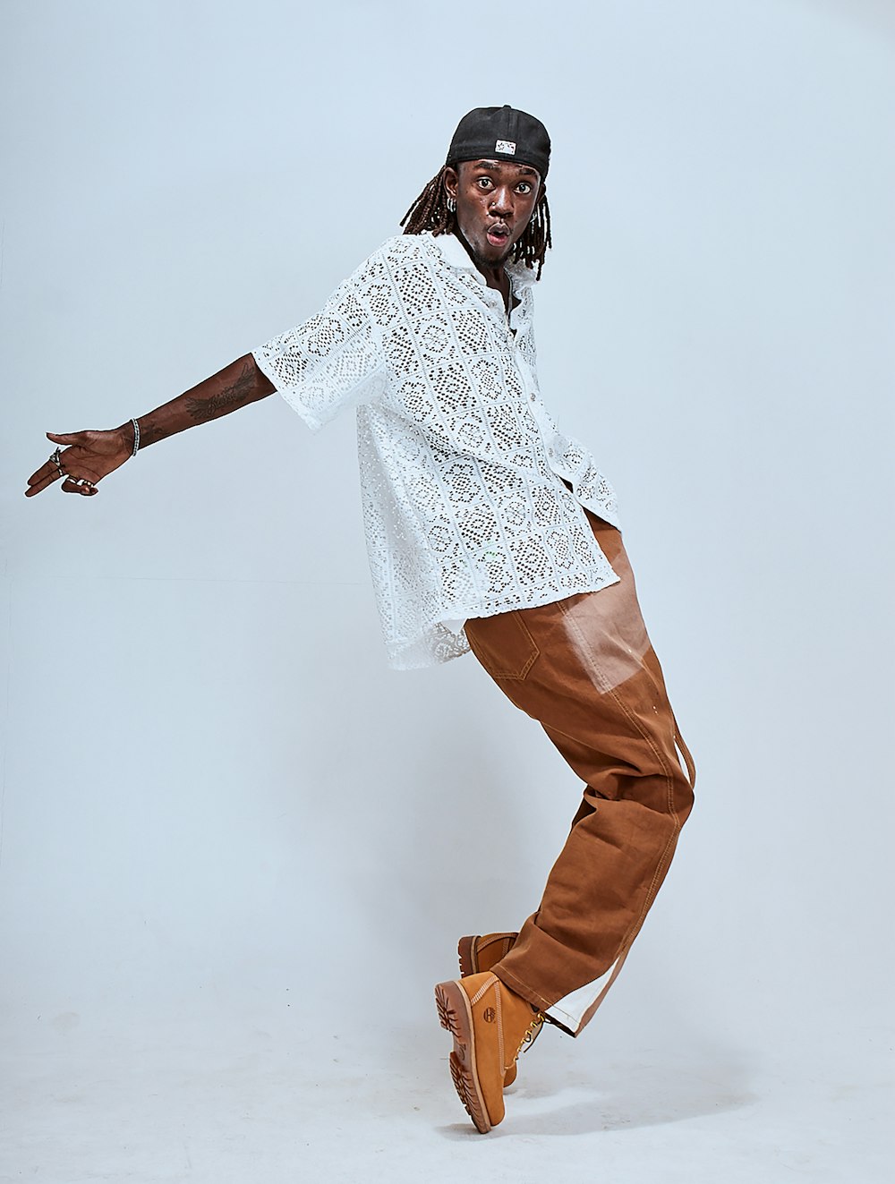 a man in white shirt and brown pants doing a skateboard trick