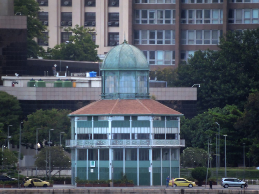 a green building with a brown roof next to a body of water