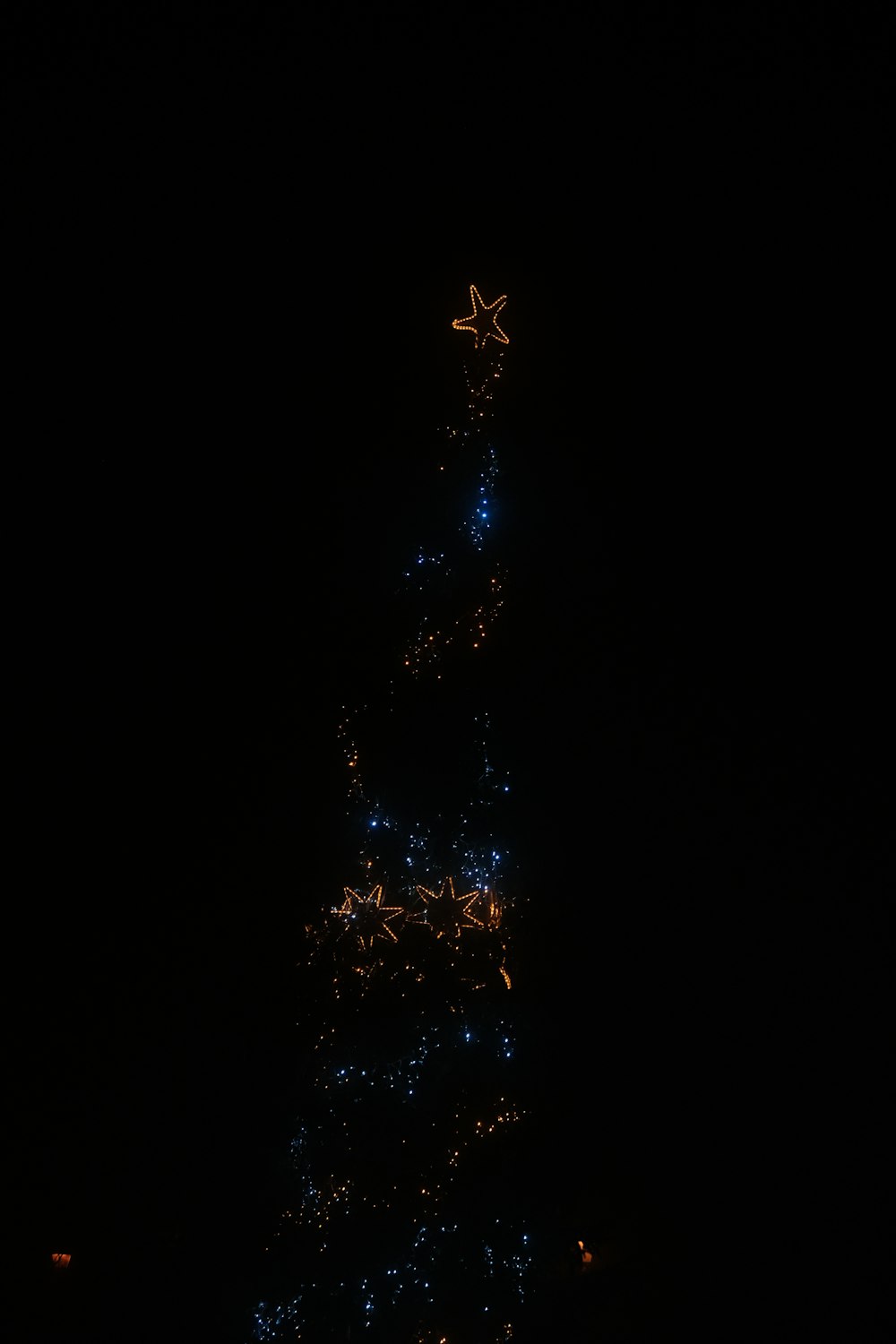 a very tall christmas tree lit up at night