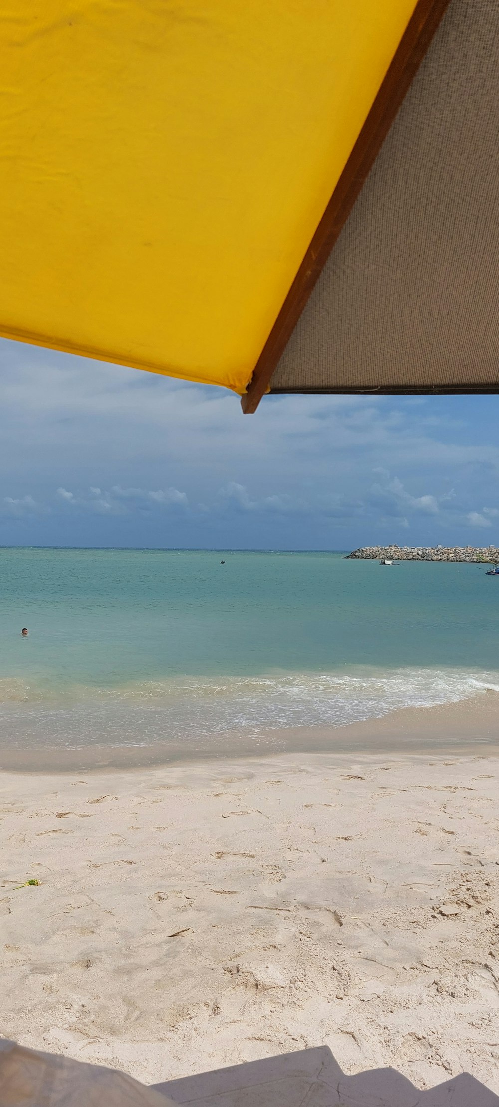 a view of the beach from under a yellow umbrella
