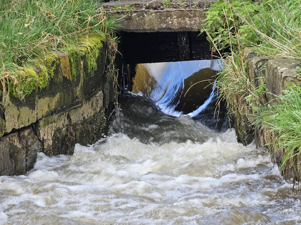 a small stream running through a stone tunnel