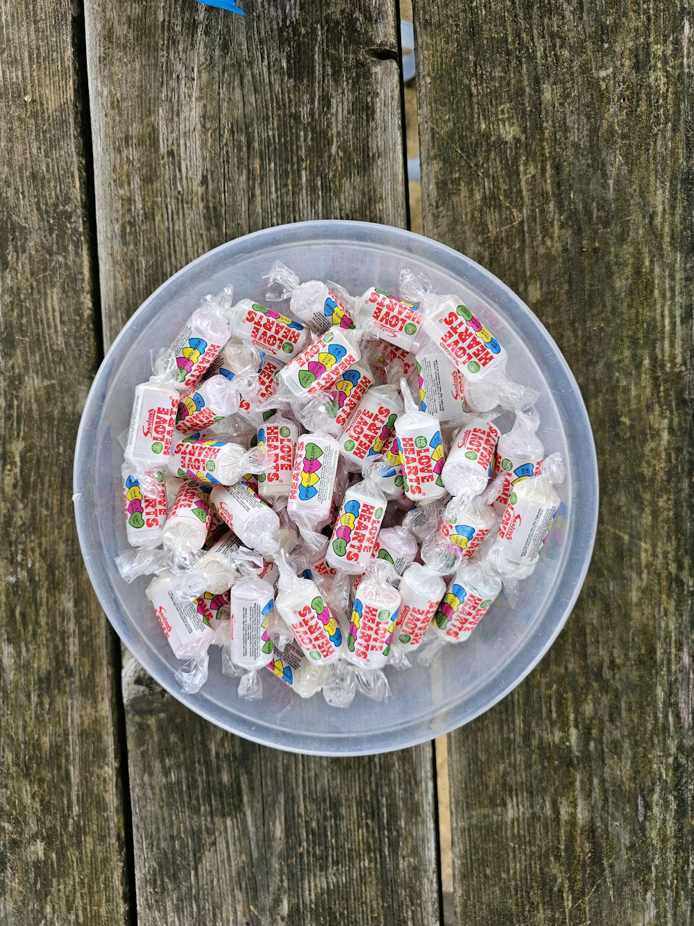a plastic bowl filled with candy on top of a wooden table