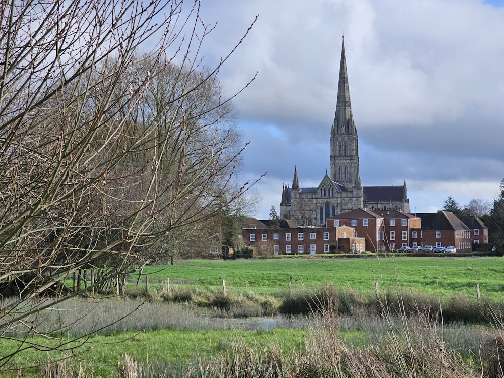 a large church with a tall steeple towering over a lush green field