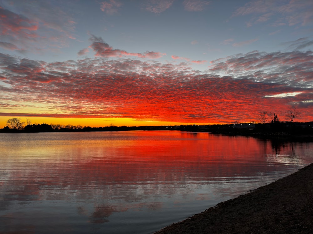 a red and orange sunset over a body of water