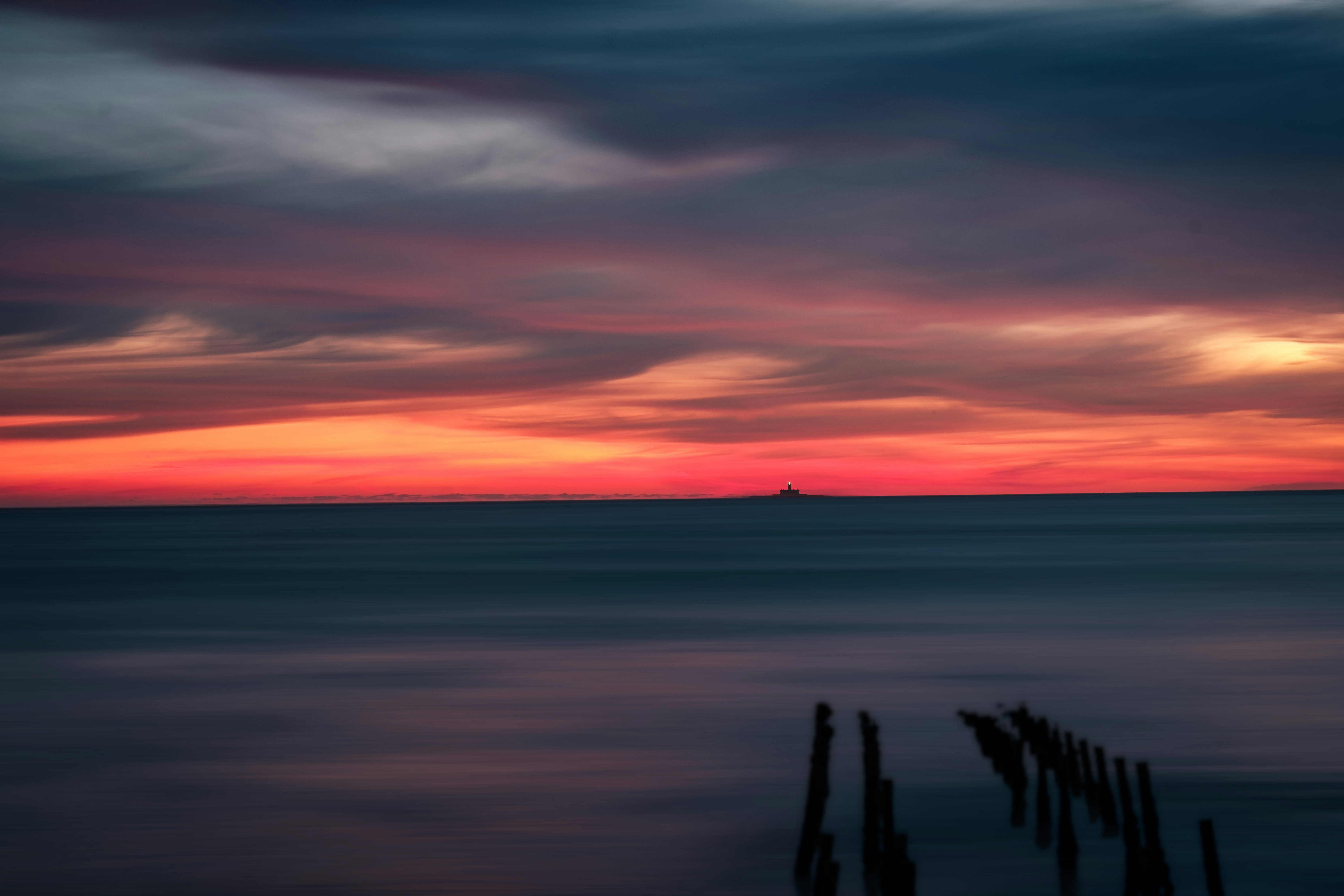 the sun is setting over the ocean with a boat in the distance