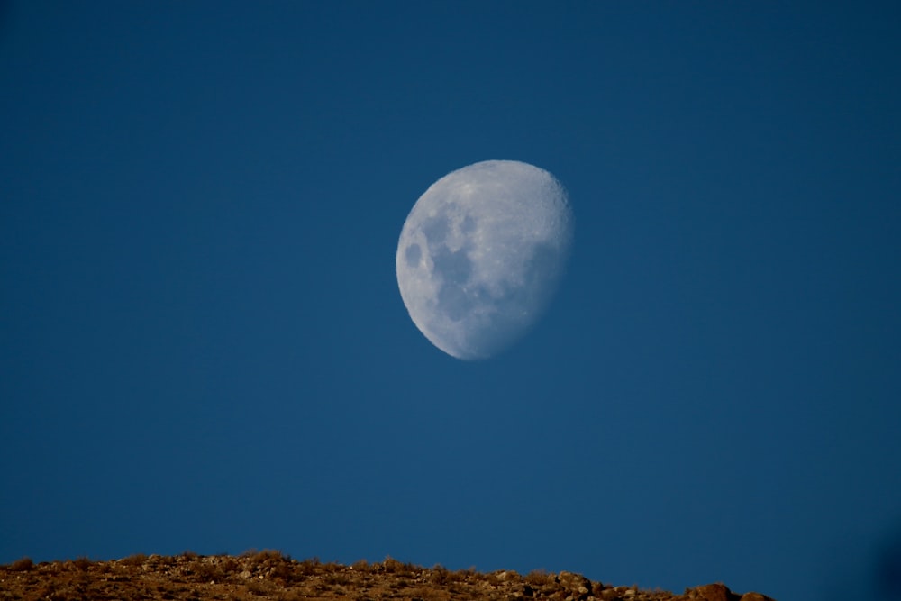 a half moon is seen in the sky above a hill