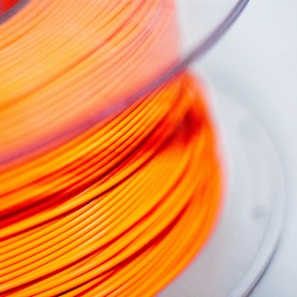 a spool of orange colored wire on a white surface