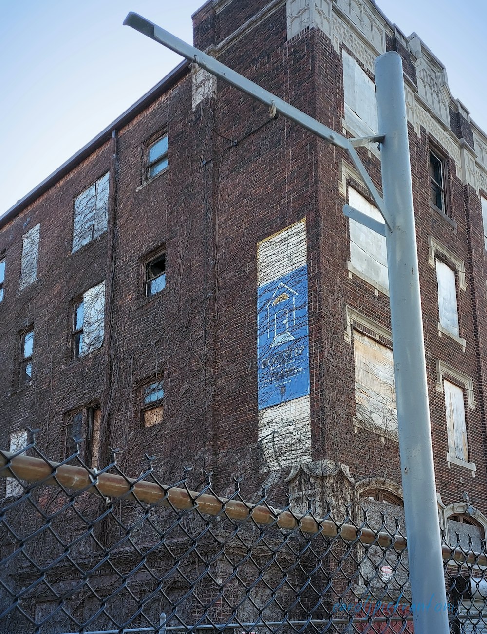 a tall brick building behind a chain link fence