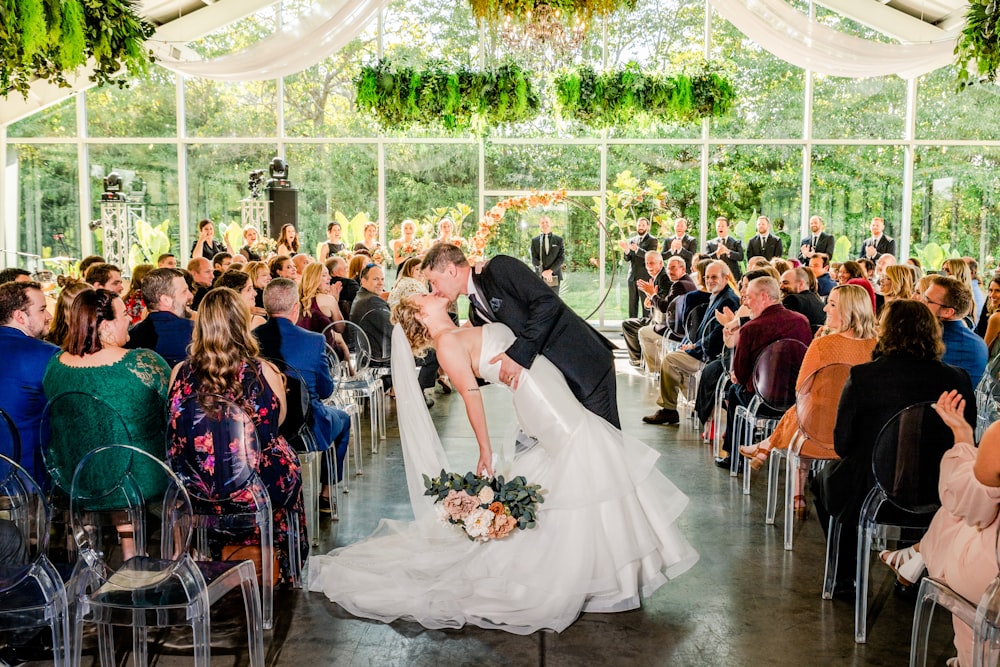 a bride and groom kiss as they walk down the aisle