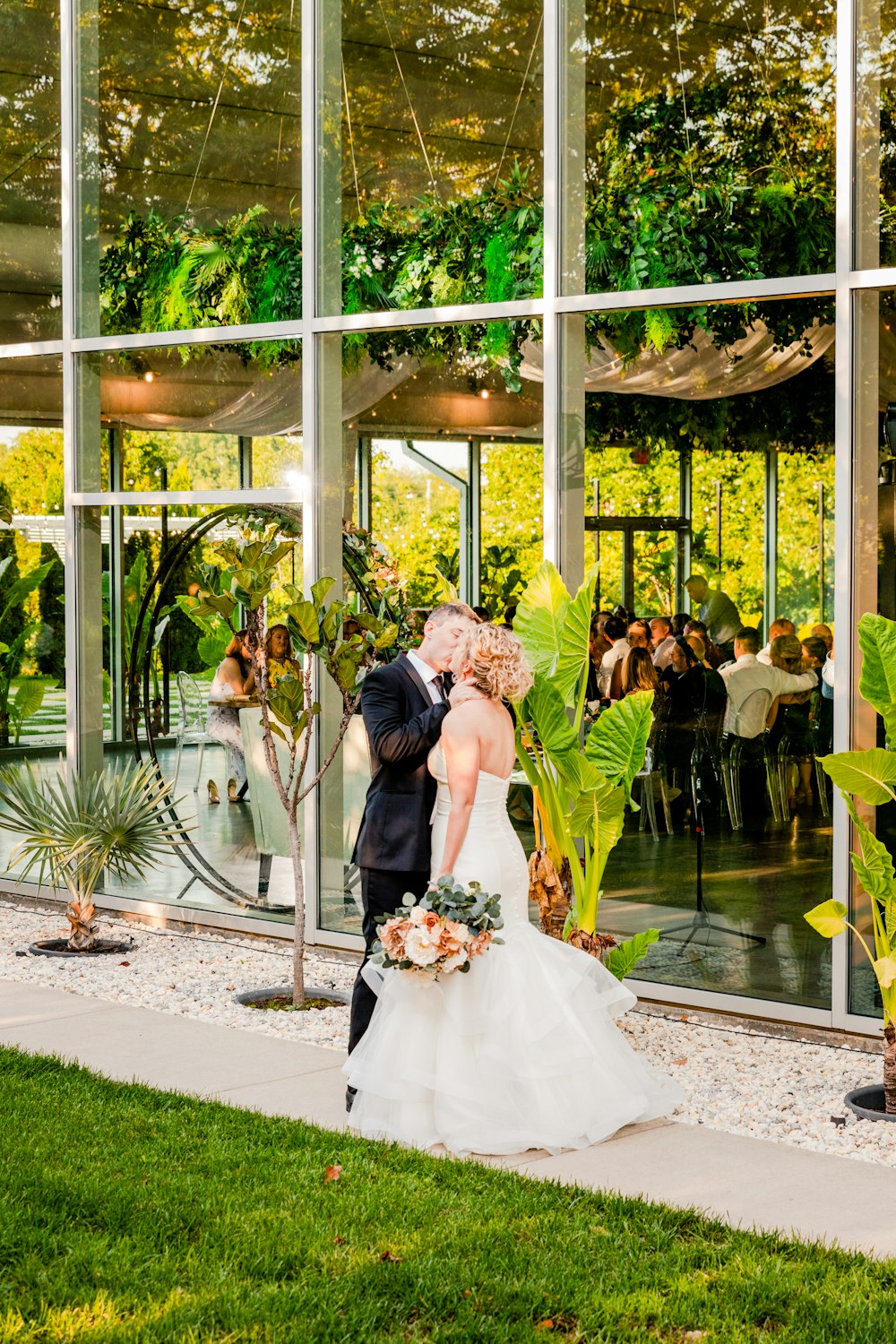 a bride and groom kissing in front of a glass building