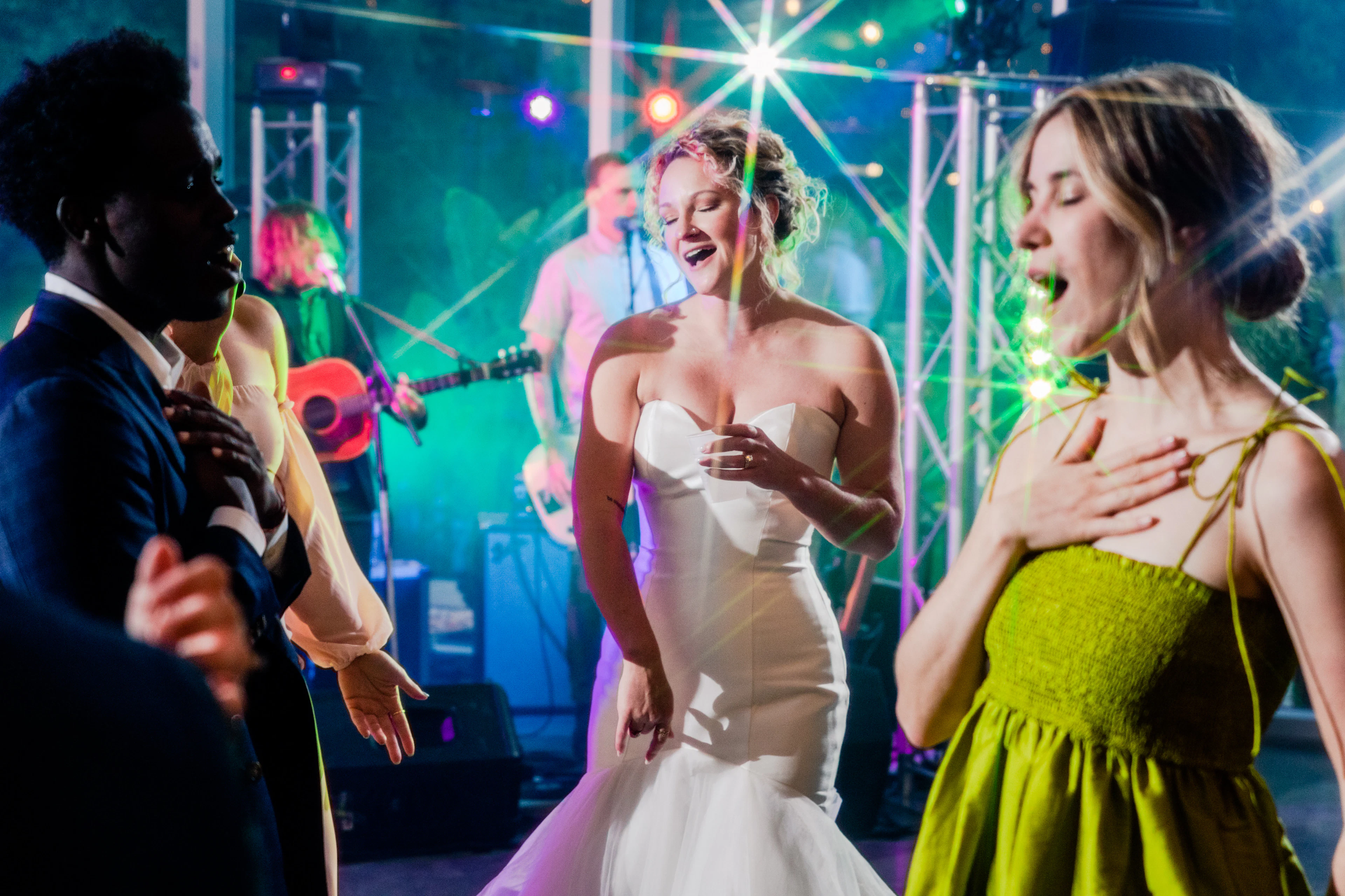 A bride and a guest dancing and laughing at a wedding reception