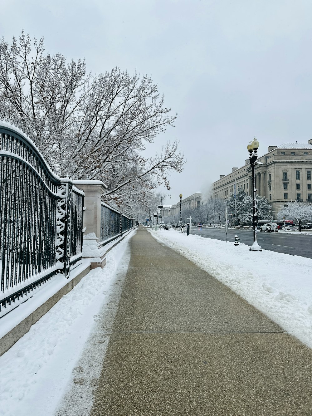 a street with a fence and a street light covered in snow