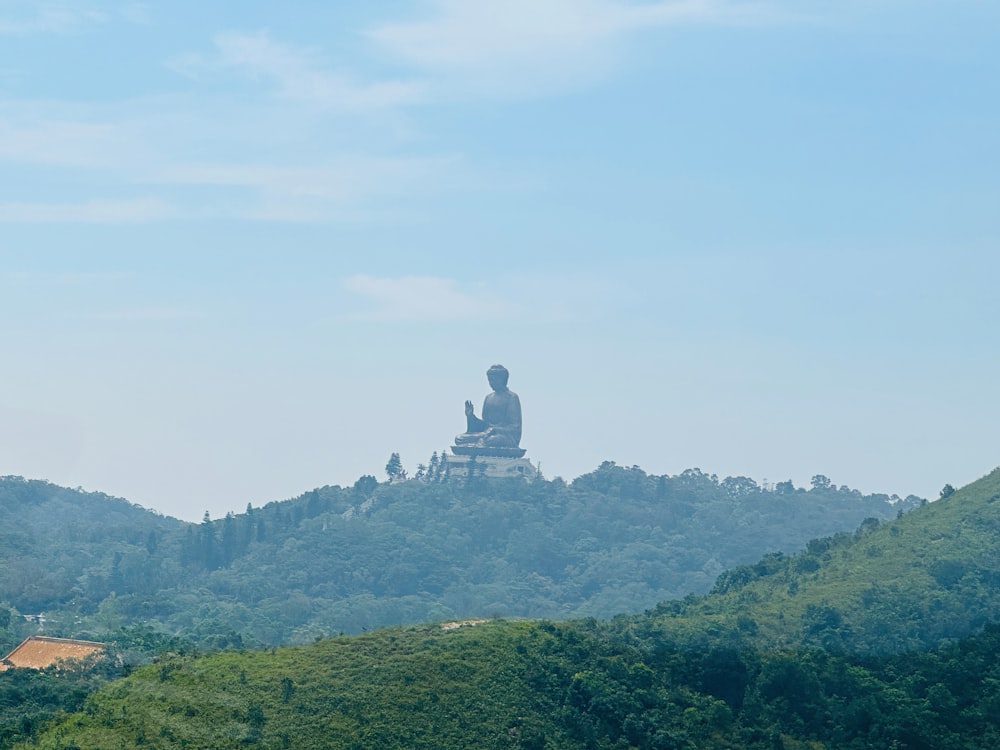 Una gran estatua de Buda sentada en la cima de una exuberante ladera verde