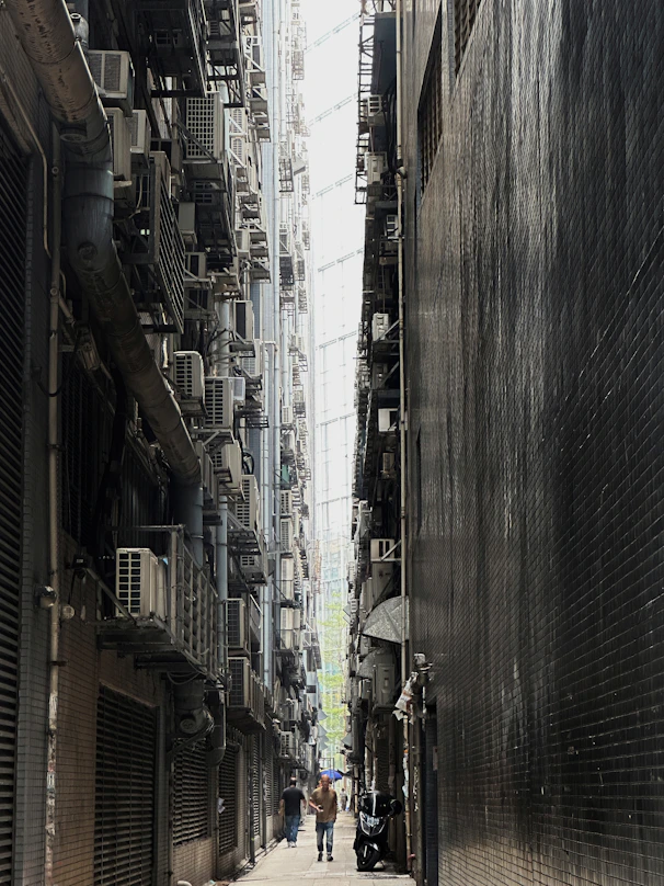 a couple of people walking down a street next to tall buildings