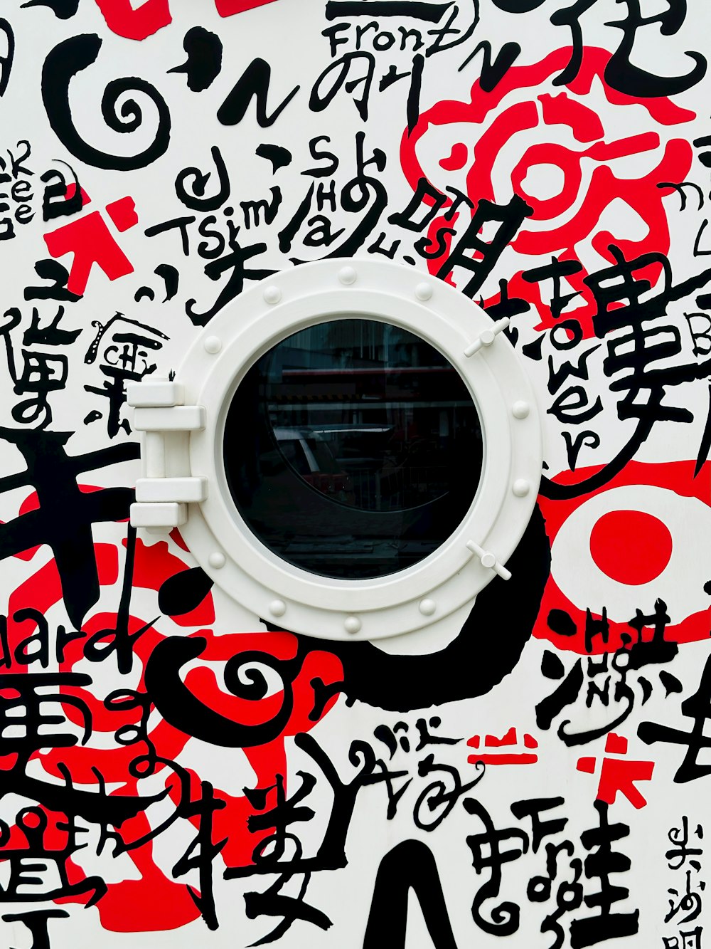 a round window in the middle of a wall covered in graffiti