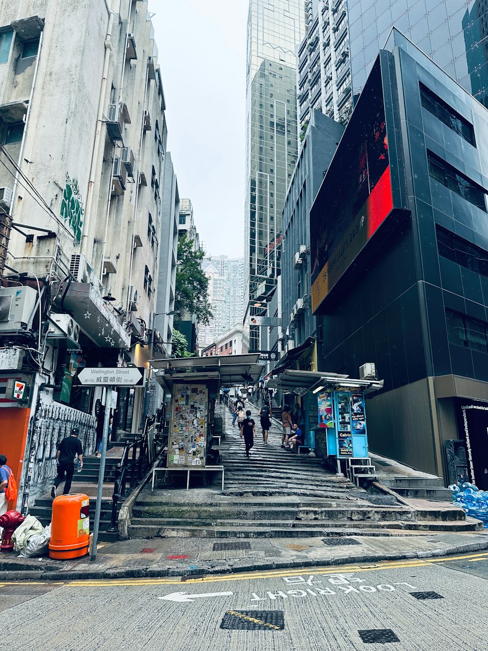 a group of people walking down a street next to tall buildings