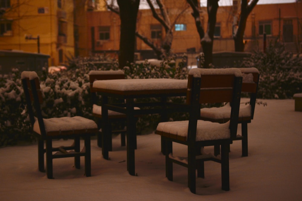 a group of chairs sitting around a table covered in snow