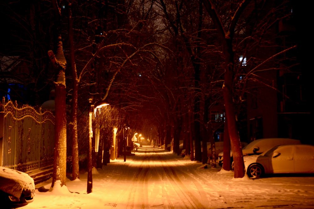 a snowy street at night with a car parked on the side of the road