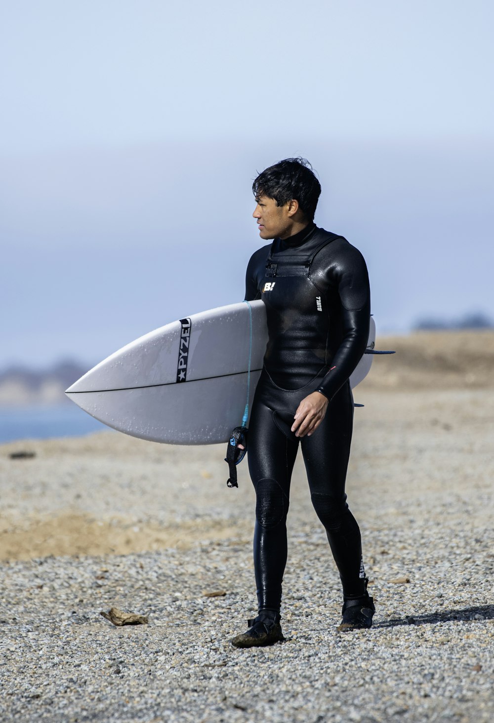 a man in a wet suit holding a surfboard