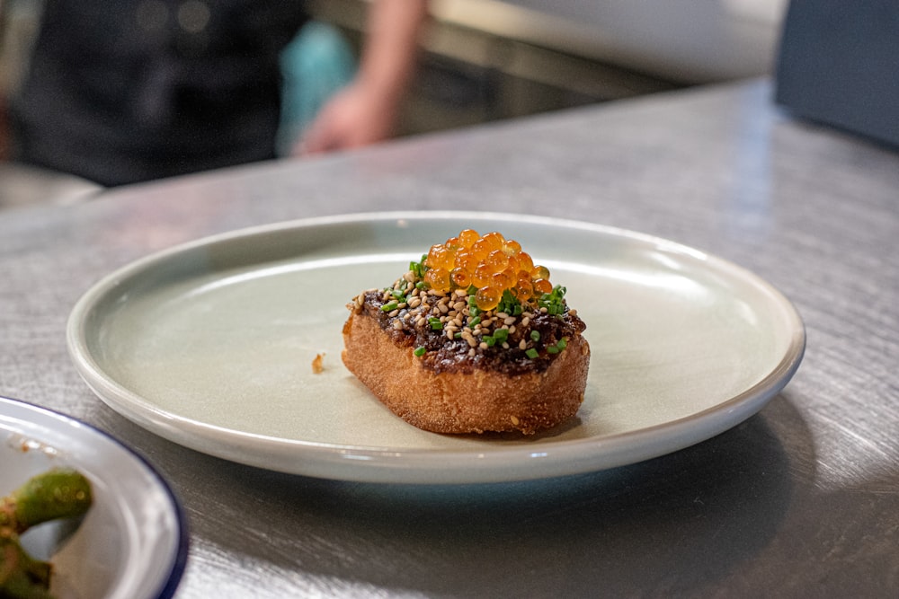 a white plate topped with a pastry covered in toppings