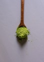a wooden spoon filled with green powder