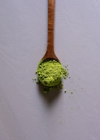 a wooden spoon filled with matcha powder