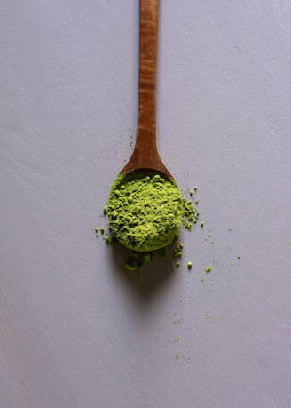 a wooden spoon filled with green powder
