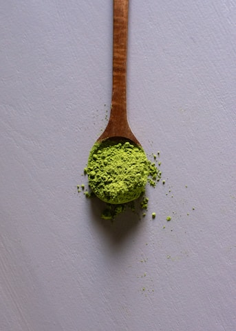 a wooden spoon filled with green powder