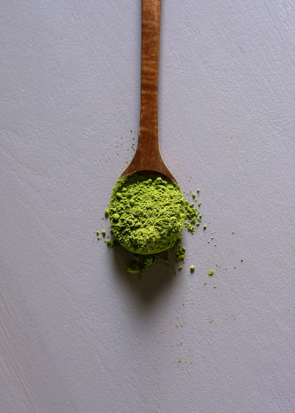 a wooden spoon filled with green powder