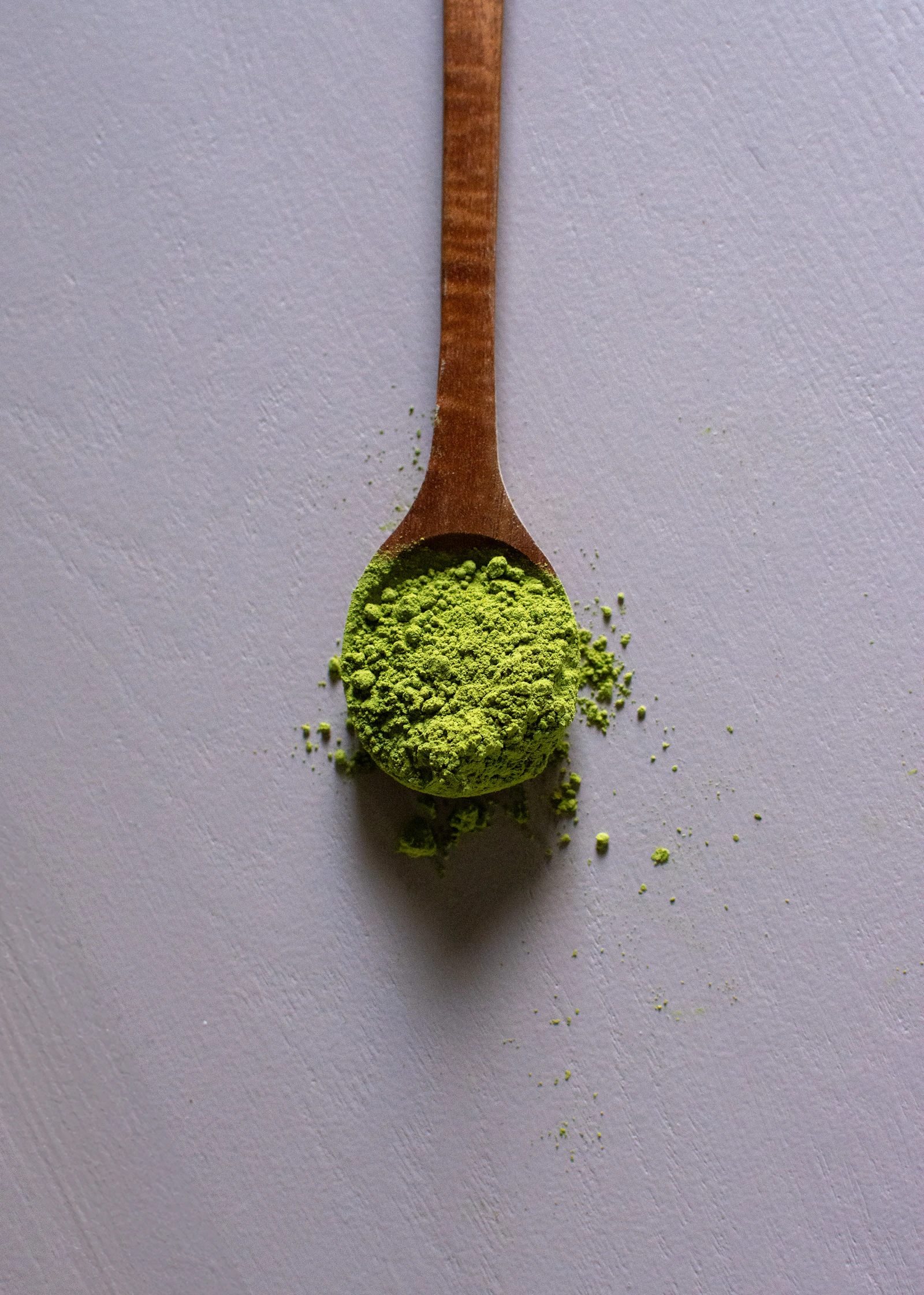 A wooden chashaku scoop holding a small mound of matcha