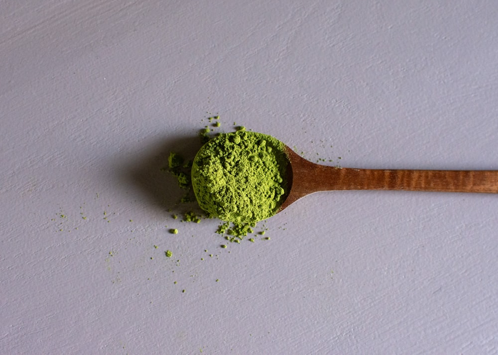 a wooden spoon filled with green powder