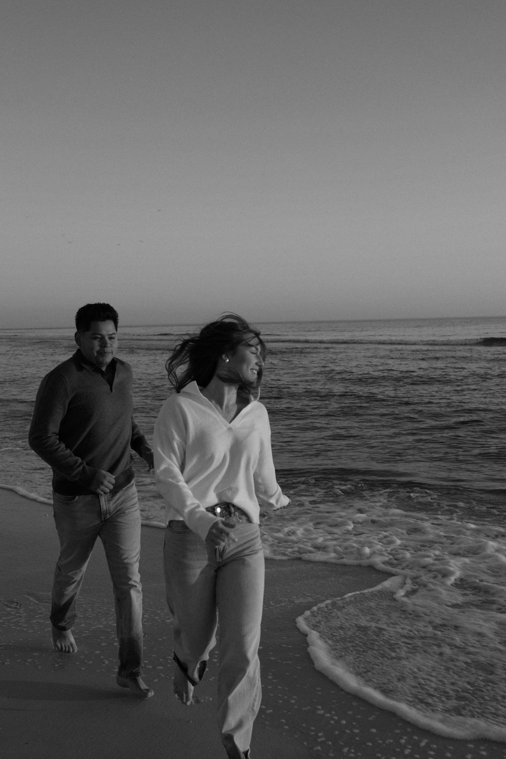 a man and a woman walking along the beach