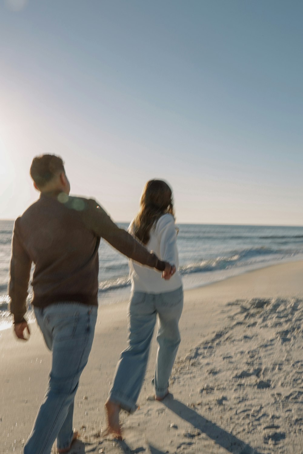 a man and a woman playing frisbee on the beach