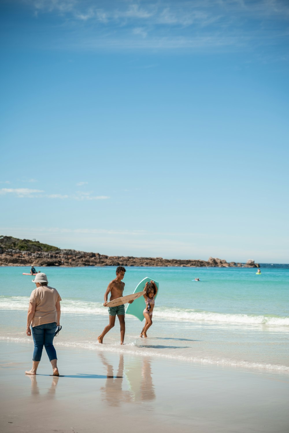 a group of people walking along a beach next to the ocean