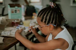 a little girl sitting at a table with a piece of paper
