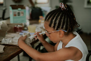 a little girl sitting at a table with a piece of paper