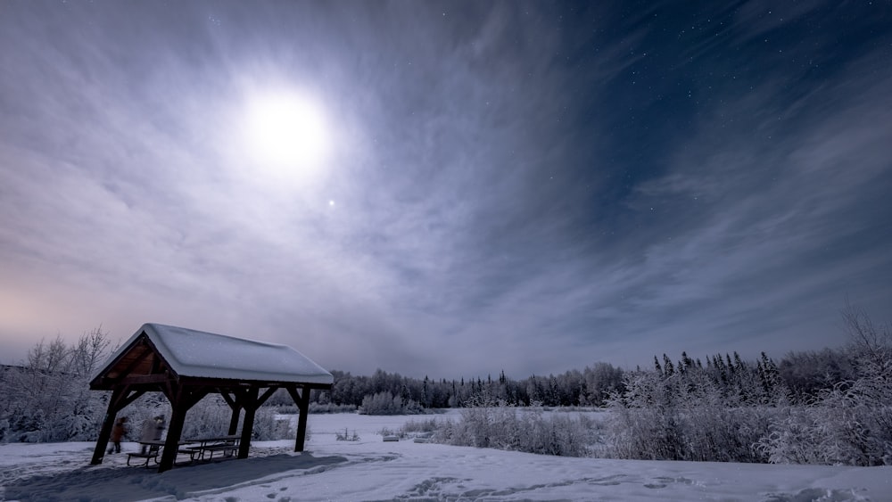 a small wooden shelter in a snowy field