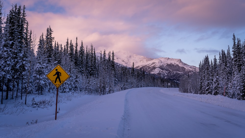 a road sign on a snowy road with a mountain in the background