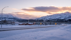 a snow covered road with mountains in the background