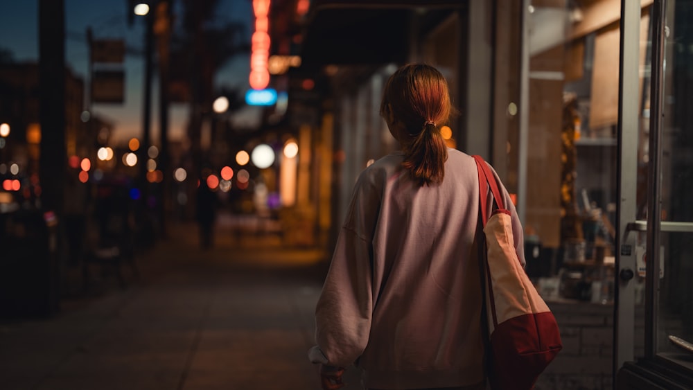 eine Frau, die nachts eine Straße entlang geht