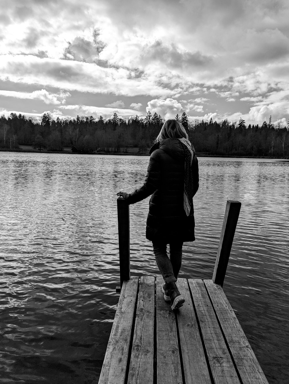 a woman is standing on a dock by the water