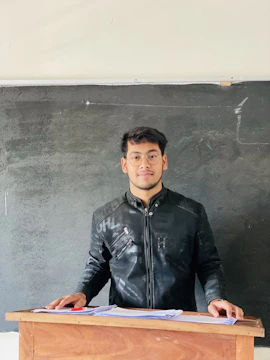 a man standing at a podium in front of a blackboard
