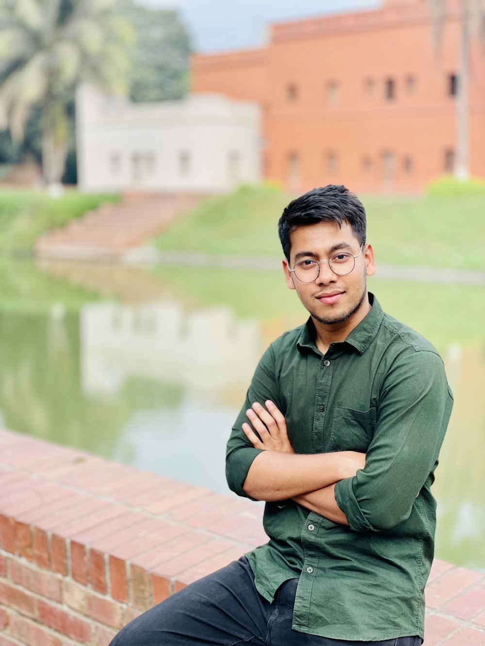 a man sitting on a brick wall with his arms crossed