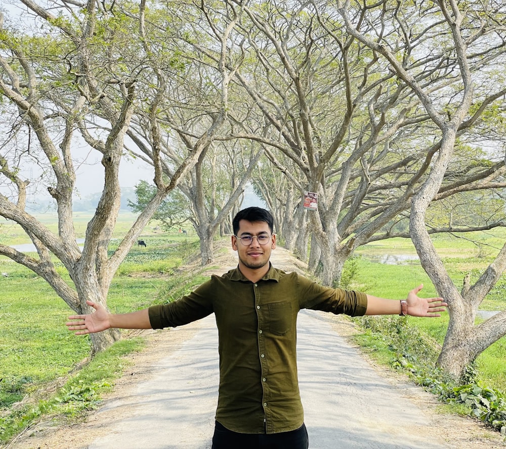a man standing in the middle of a tree lined road