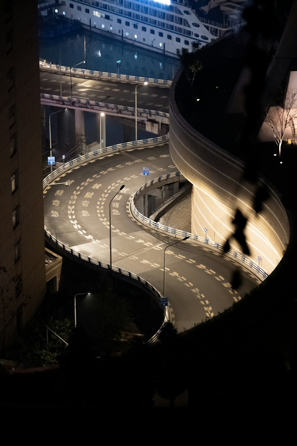 una calle de la ciudad por la noche con un gran edificio al fondo