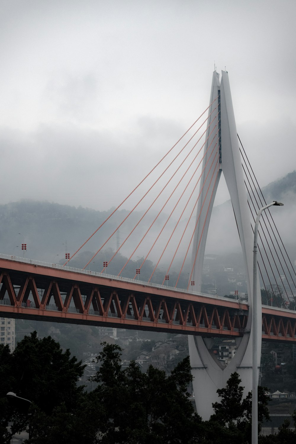 Eine große Brücke, die sich über eine Stadt mit Bergen im Hintergrund spannt