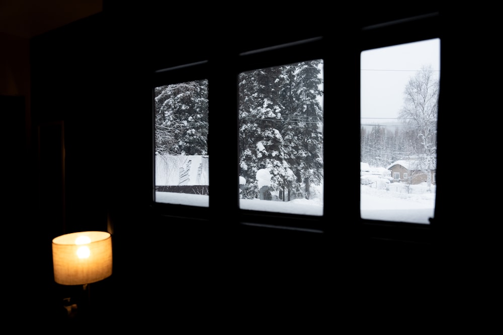 a candle is lit in front of three windows in a dark room
