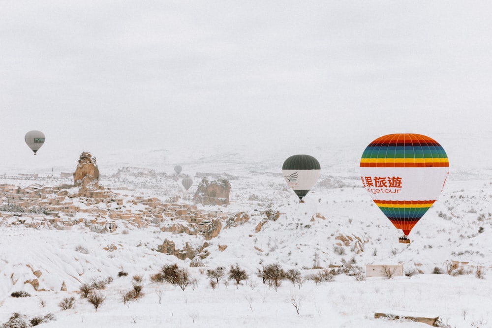 Eine Gruppe von Heißluftballons fliegt über ein schneebedecktes Feld