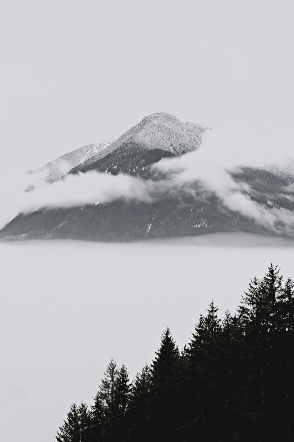 une photo en noir et blanc d’une montagne couverte de nuages